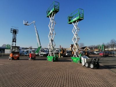 Baugeräte und Baustellenbedarf mieten - Zwei grüne Scherenarbeitsbühnen und ein orangener Gabelstapler stehen auf einem Parkplatz