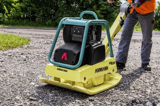 Baumaschinen mieten - Gelbe Rüttelplatte die von einem Mann mit orangener Weste bedient wird