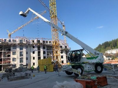 Baugeräte und Baustellenbedarf mieten - Weisser Teleskoplader auf einer Baustelle