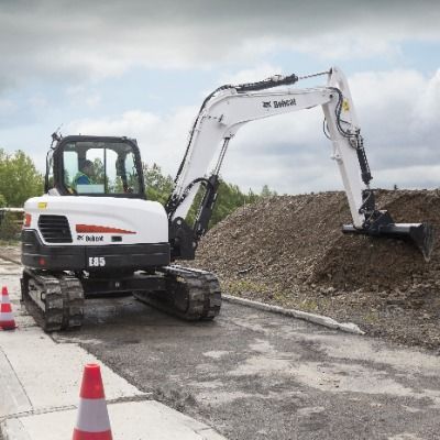 Baugeräte und Baustellenbedarf mieten - Weisser Raupenbagger von der Marke Bobcat gräbt ein Loch mit der Schaufel